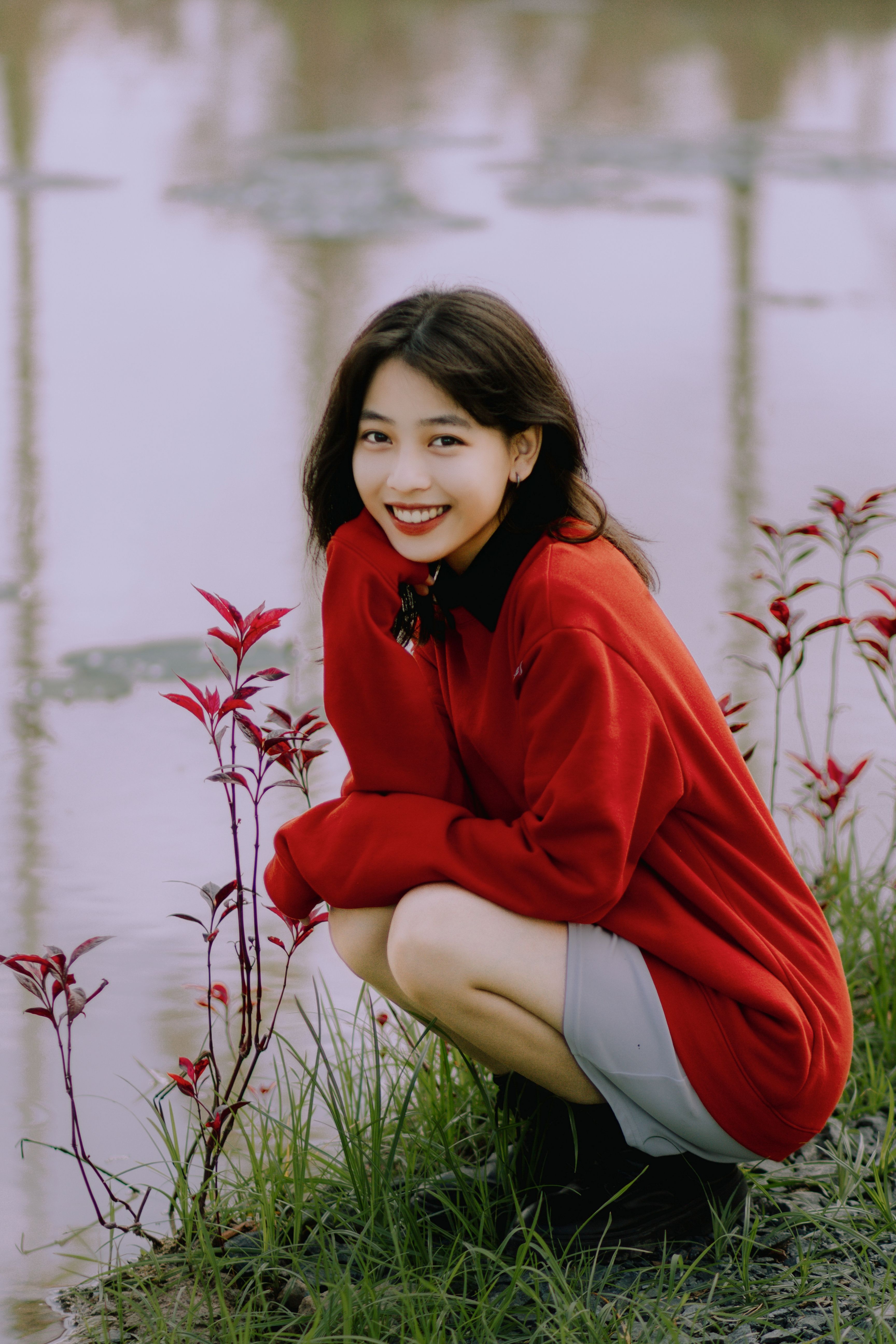 Smiling Woman in Red Clothes Squatting by Water · Free Stock Photo