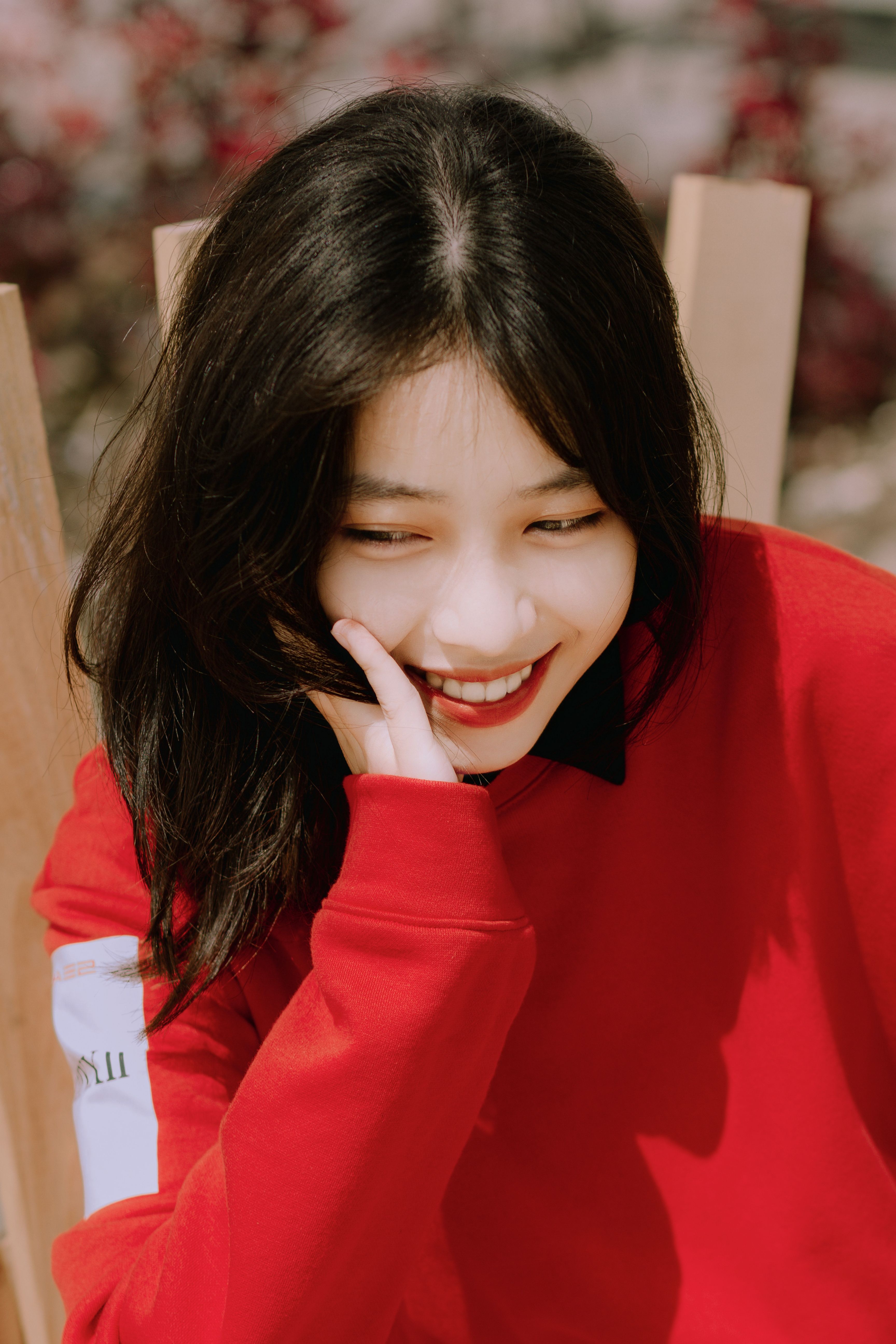 Portrait of a cheerful woman with long black hair in a red sweater enjoying the outdoors.