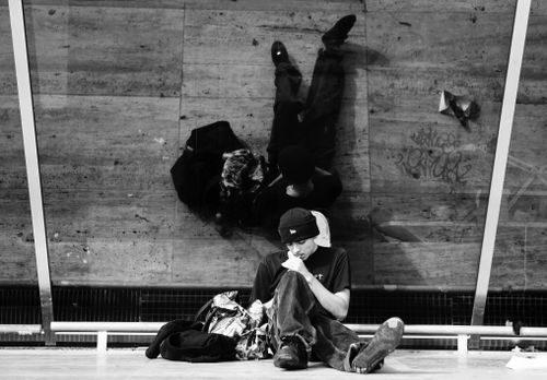 Free A man sits in an urban setting with his reflection visible in a mirror behind him, creating a unique perspective. Stock Photo