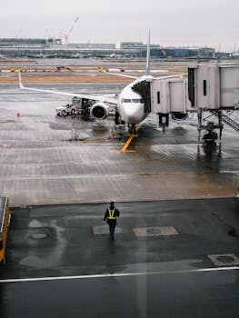 下雨天，一名地勤人员正行走在停着飞机的机场门口