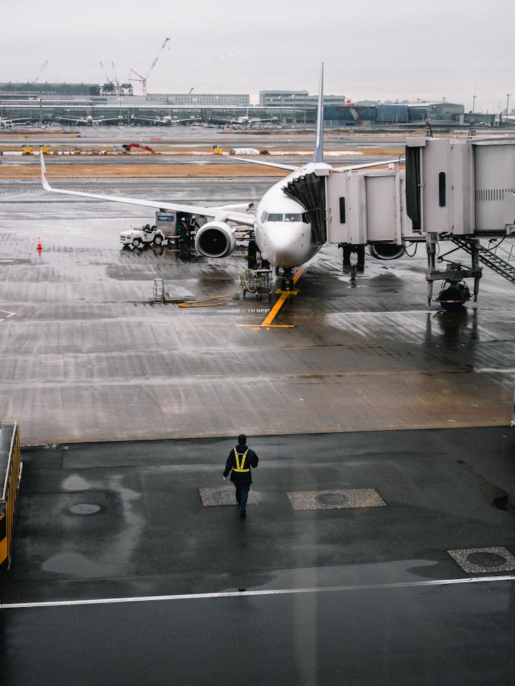 Person Walking Towards Airplane On Airport