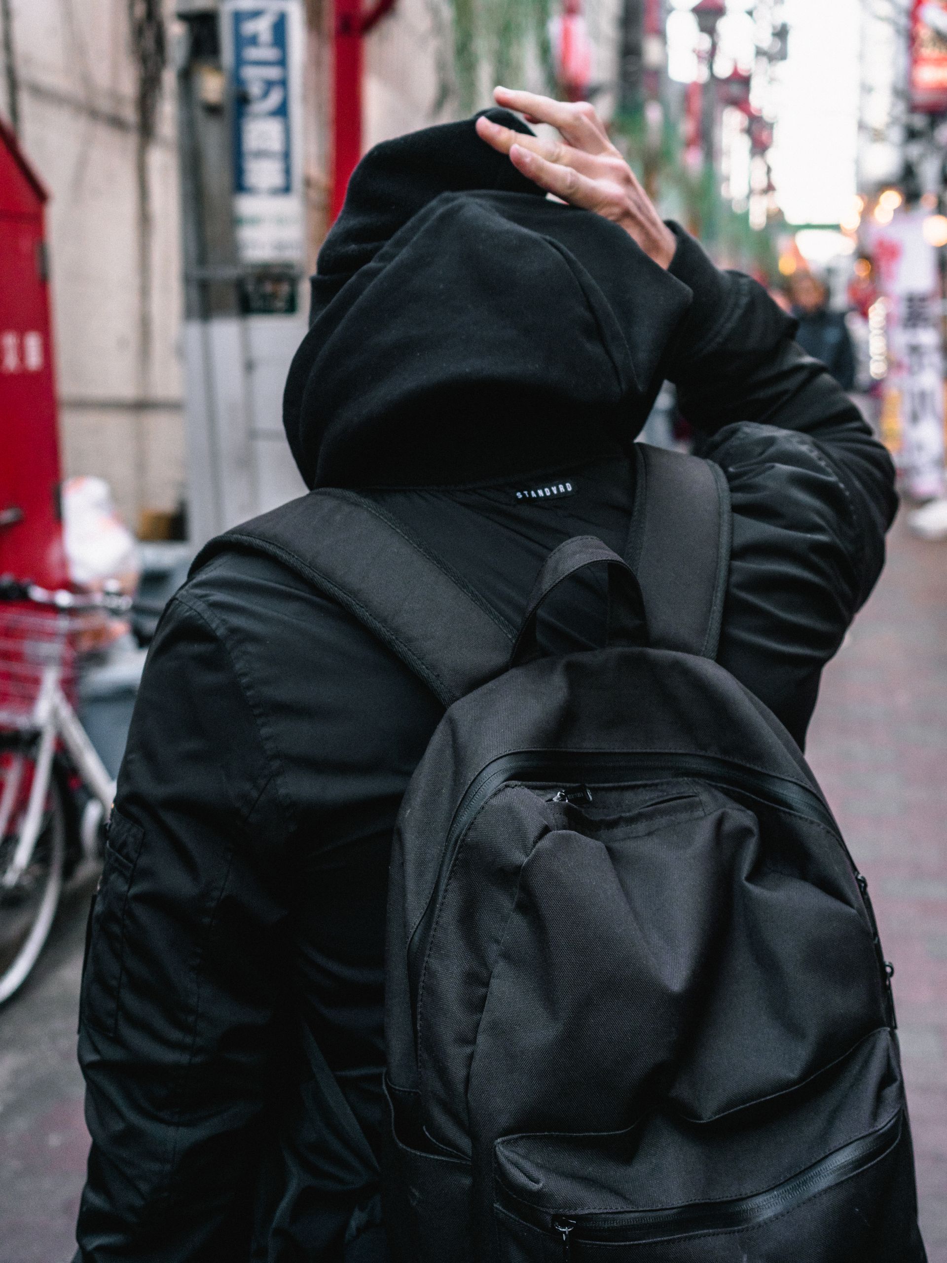 Pessoa de moletom preto e mochila na rua