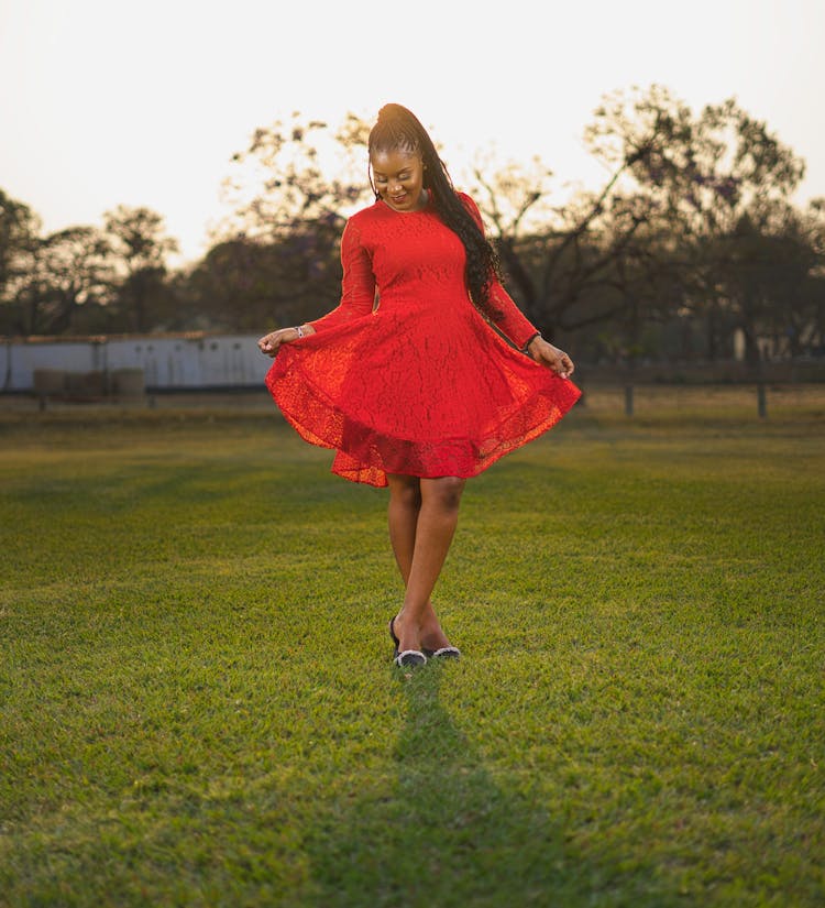 Beautiful Woman In Red Dress Posing On Lawn In Park