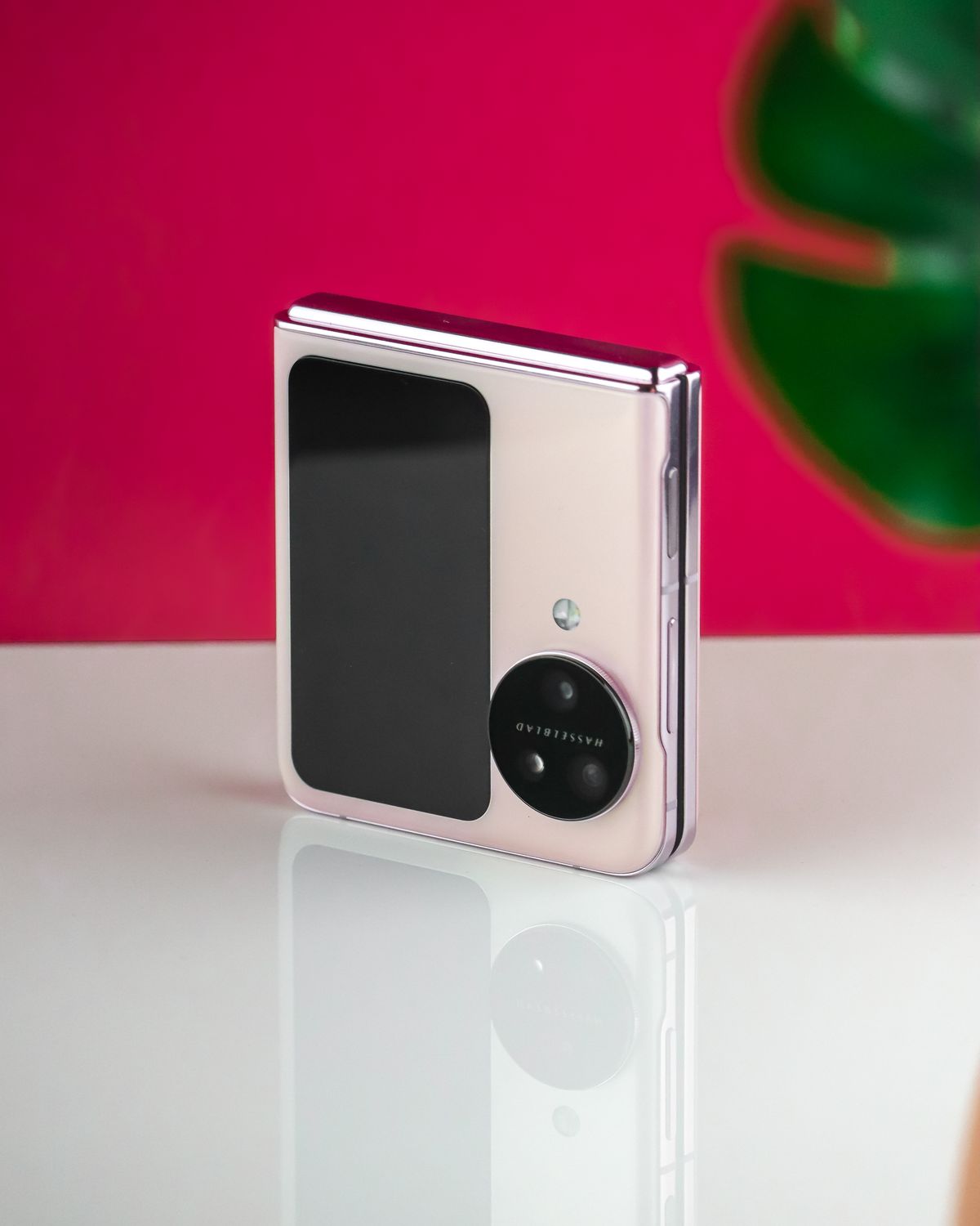 A foldable smartphone against a pink background