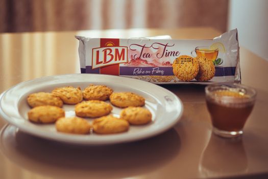 A tempting tea setup with LBM tea time biscuits and a glass of tea on a table.