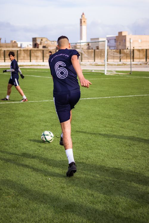 Free A soccer player in sportswear kicks a ball on a grass field during daytime practice. Stock Photo