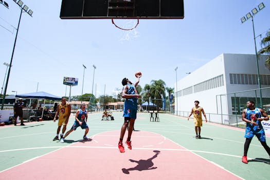 Players in action during an outdoor basketball game, showcasing athleticism and teamwork on a sunny day.