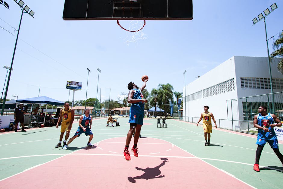 Players in action during an outdoor basketball game, showcasing athleticism and teamwork on a sunny day.