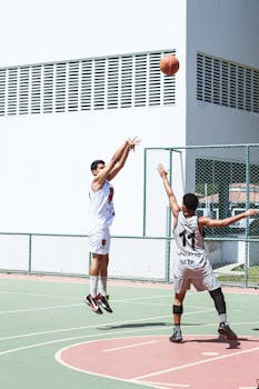 Two players compete in an outdoor basketball game, capturing the action and energy.