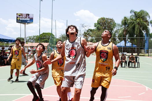 A group of young men playing an intense basketball game outdoors under a clear sky.