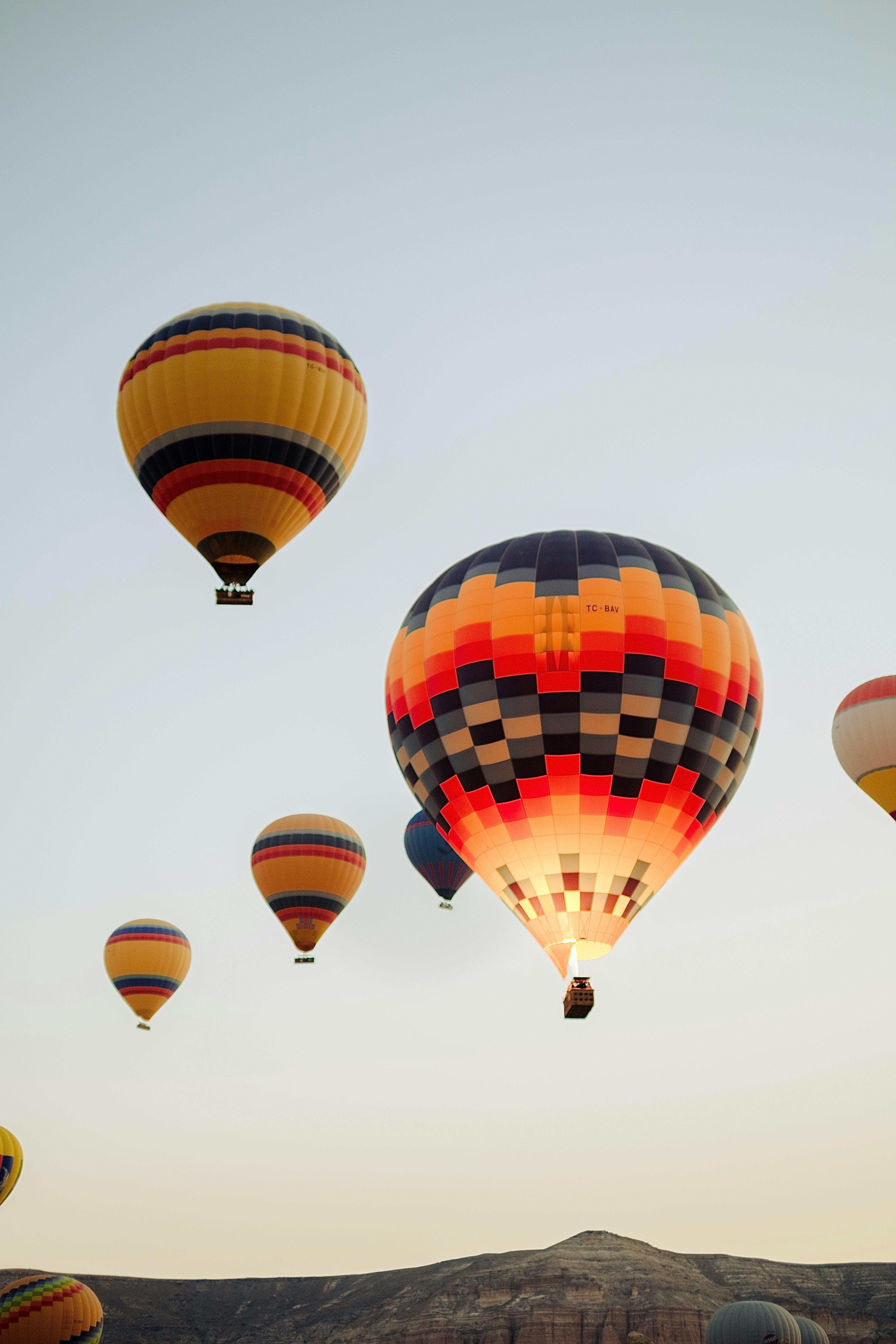Vibrant hot air balloons soaring over the scenic Cappadocia landscape in Türkiye.