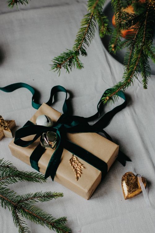 Free Stylish gift with green ribbon and pine decor for a cozy Christmas feel. Stock Photo