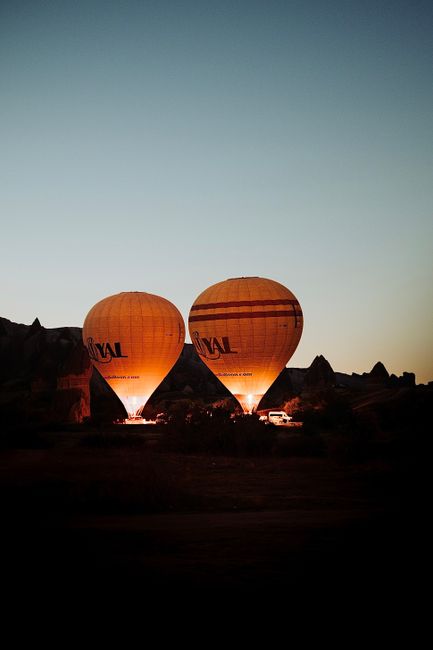 Captivating view of illuminated hot air balloons preparing for flight in Göreme, Türkiye at dawn.