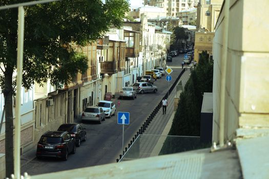 A daytime scene of a street in Baku, showcasing urban architecture and parked cars.