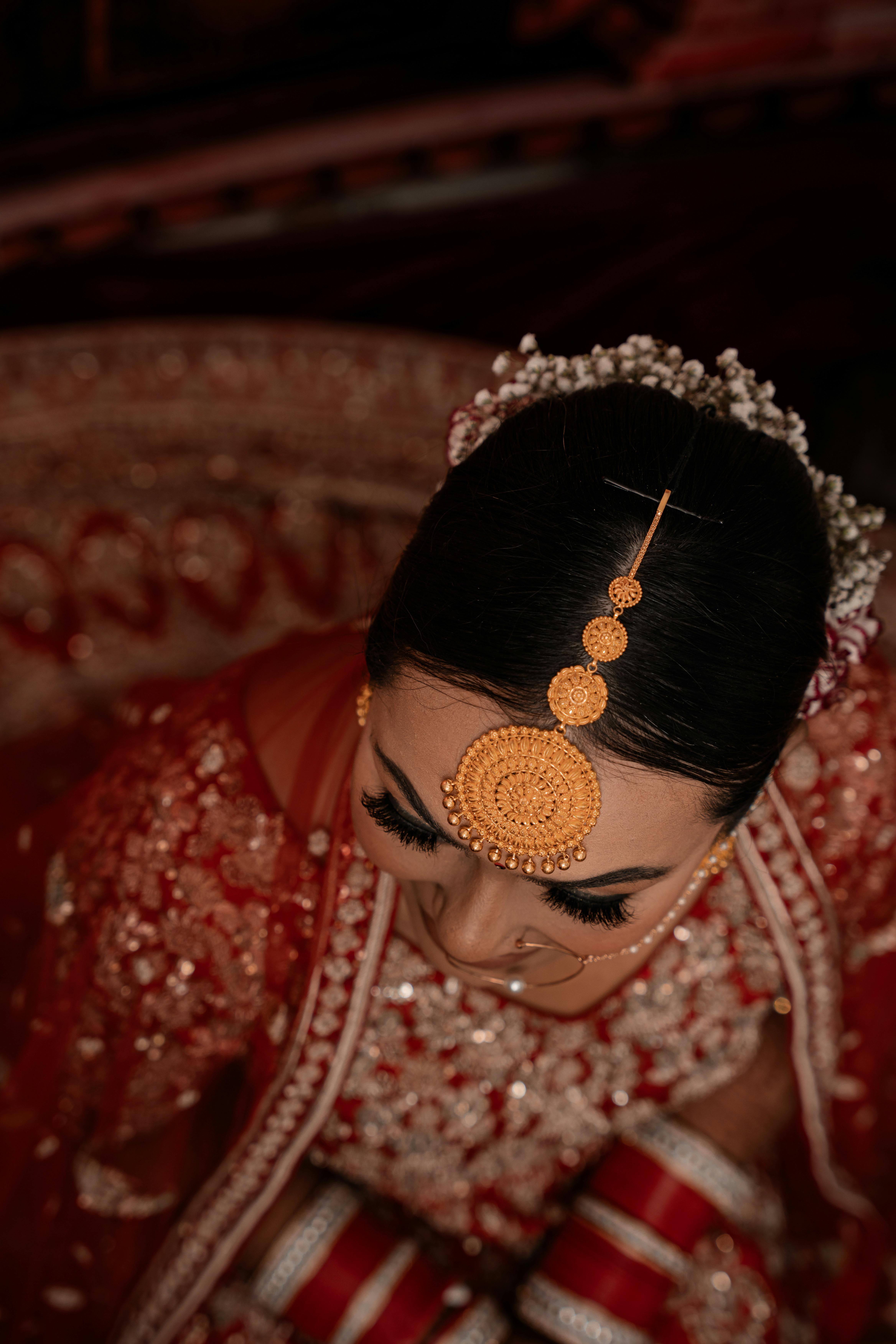 Close-up of a bride in traditional Indian attire with intricate jewelry and design.