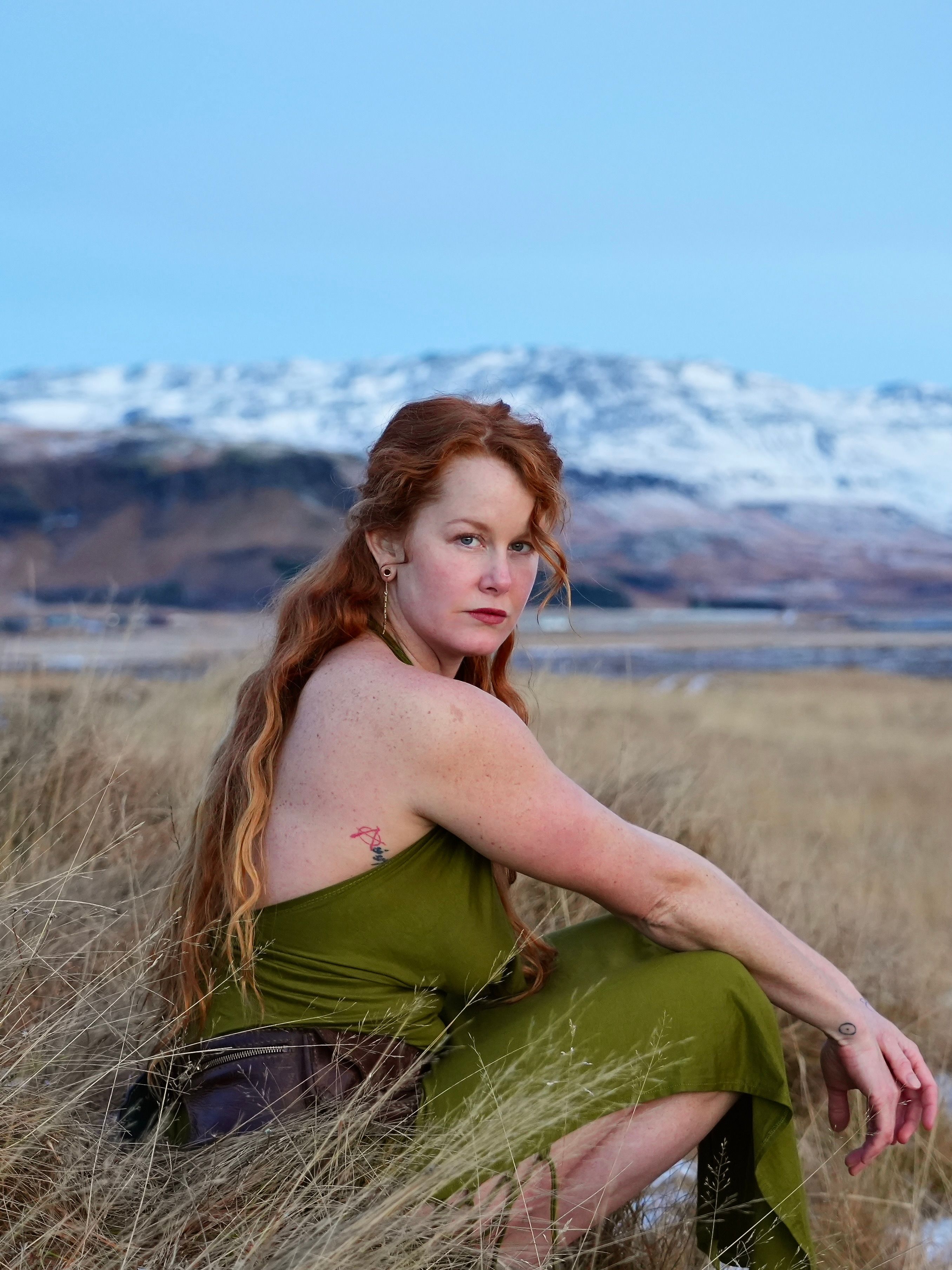 A woman in a green dress sitting in a field · Free Stock Photo