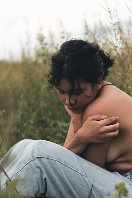 Young Woman Sitting Topless on a Meadow 