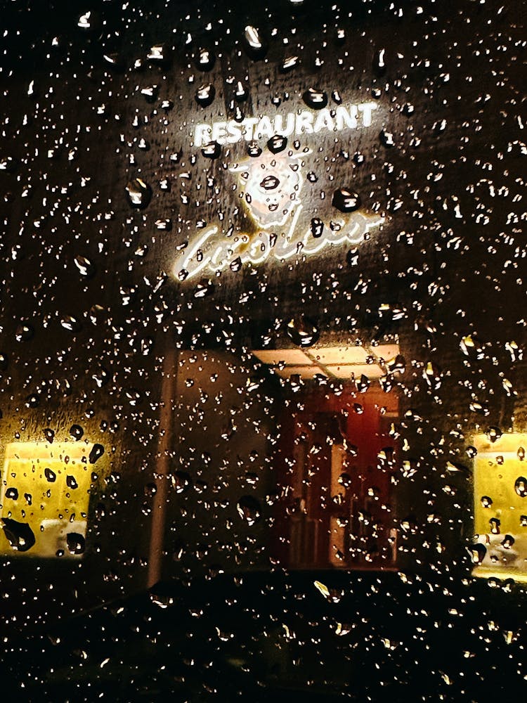 Restaurant Logo Behind Raindrops On Window At Night