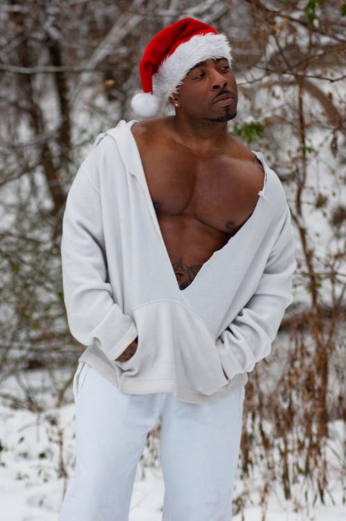 Man Dressed in White with Santa Hat in Winter Forest