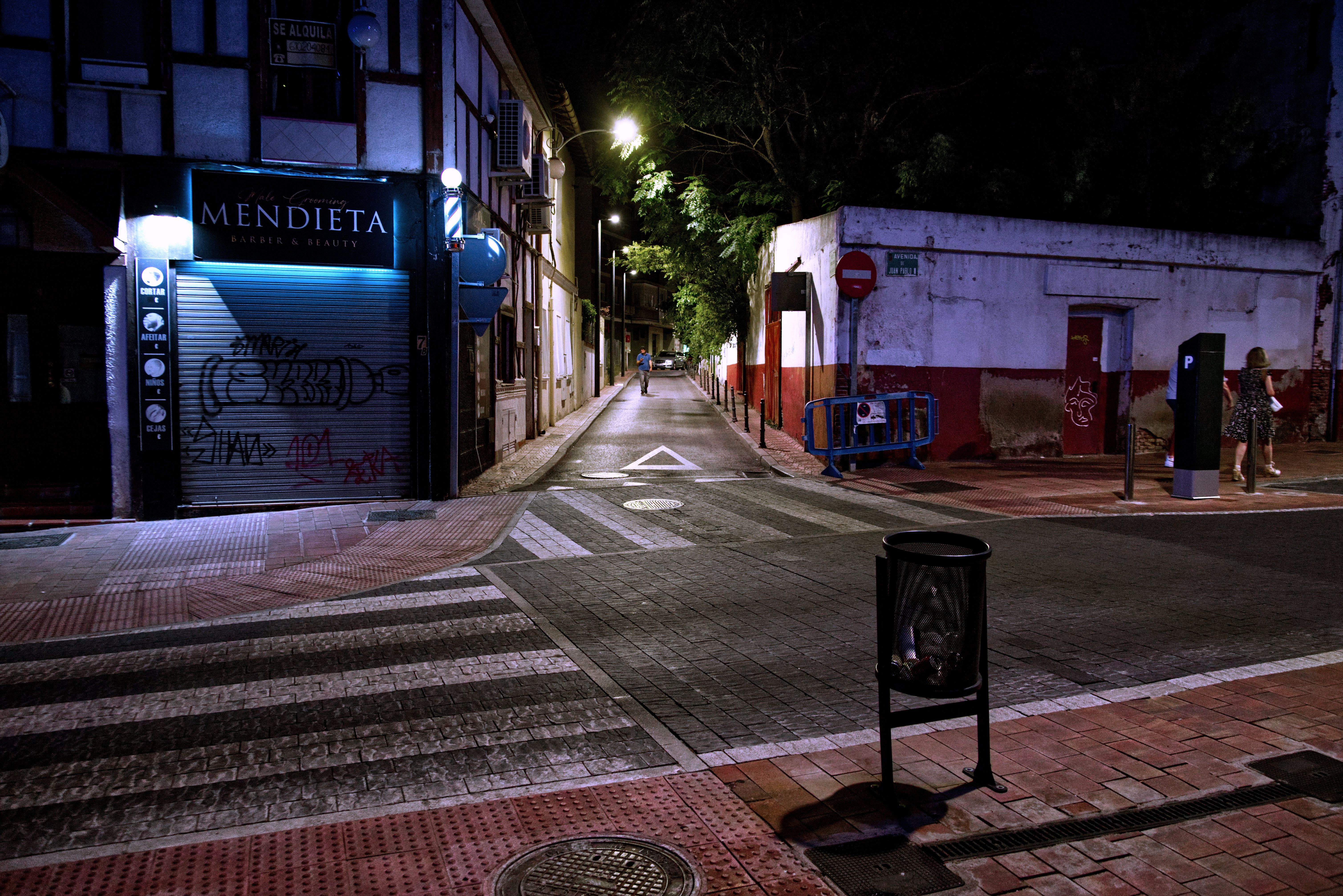 Quiet urban street scene at night with graffiti and closed storefronts.