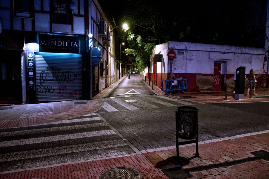 Quiet urban street scene at night with graffiti and closed storefronts.