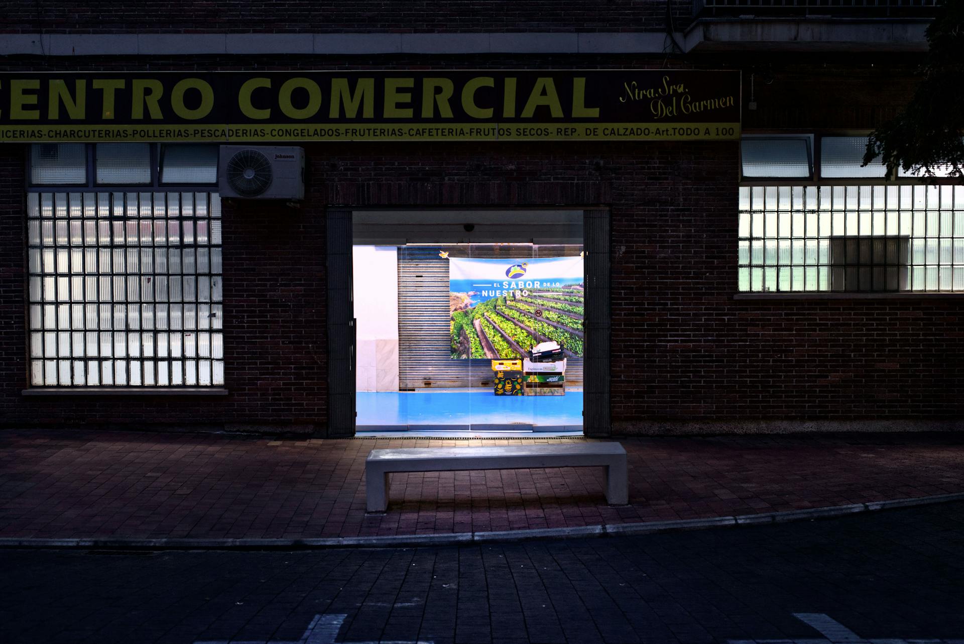 A vibrant night view of a commercial center entrance in a city setting.