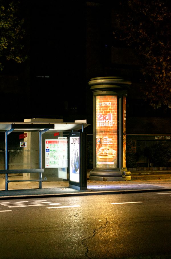 Illuminated poster column and bus shelter at night