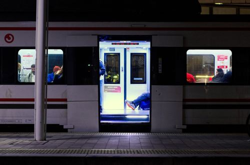 Free Passengers relax inside a train at a dimly lit urban station during nighttime. Stock Photo