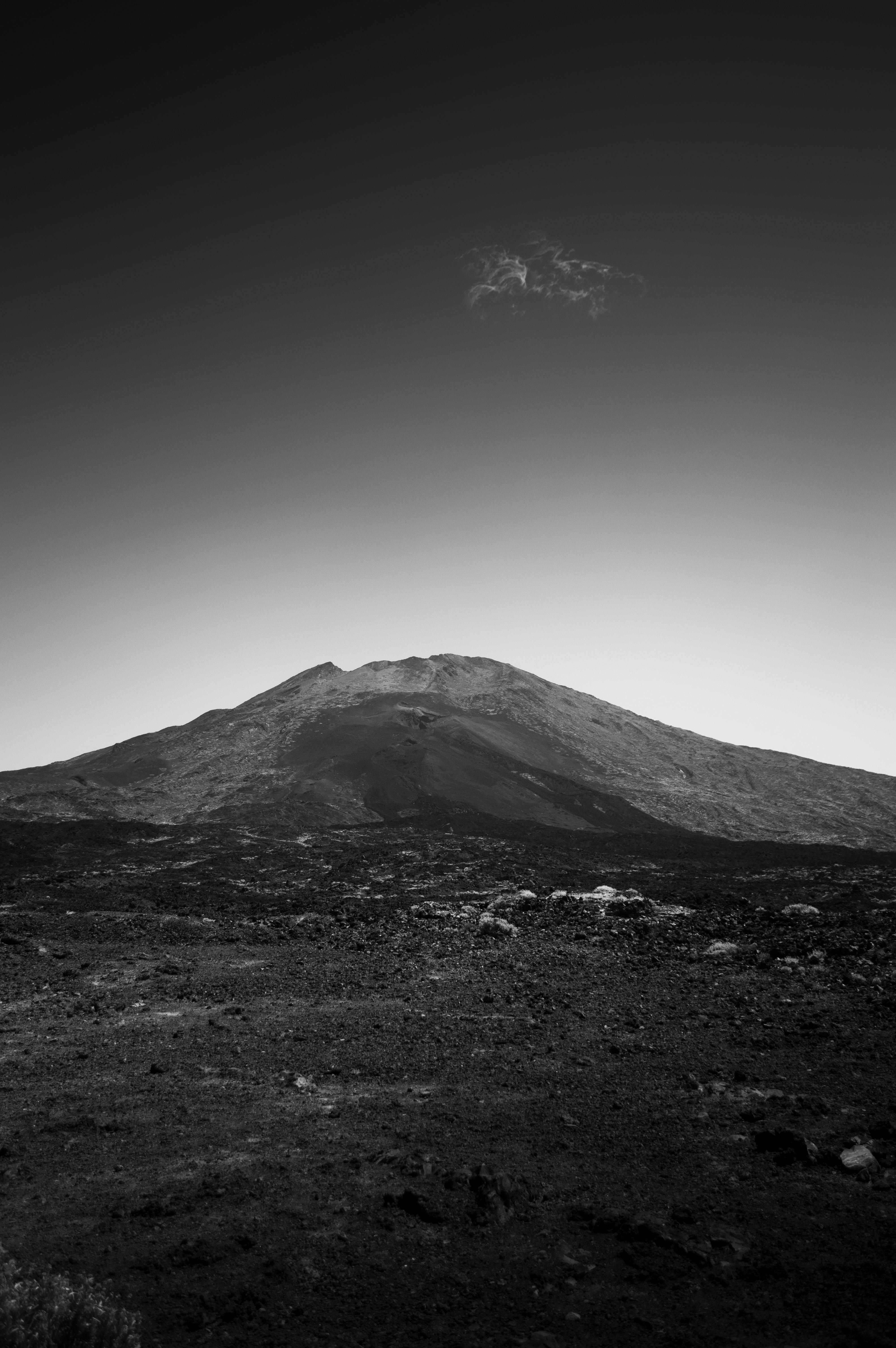 A dramatic black and white photograph showcasing a barren volcanic mountain slope.