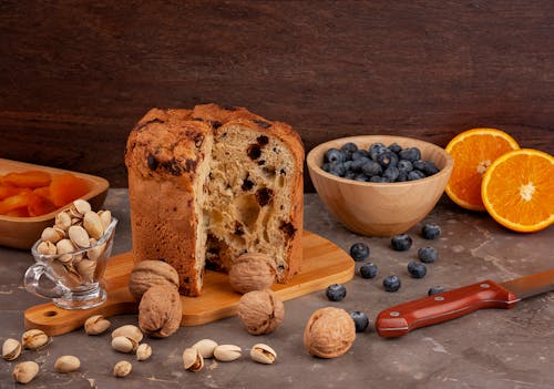 Free Panettone Cake on a Cutting Board Among Fruits and Nuts Stock Photo