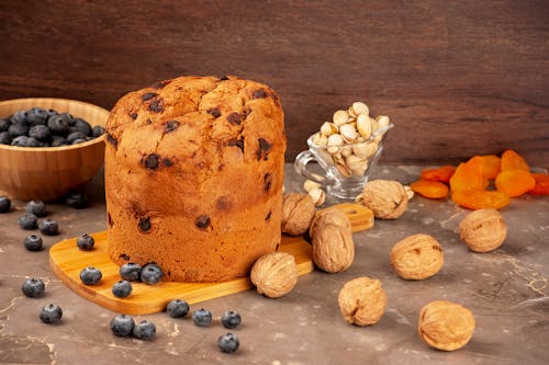Walnuts and Blueberries Scattered Around a Cutting Board with Panettone Cake