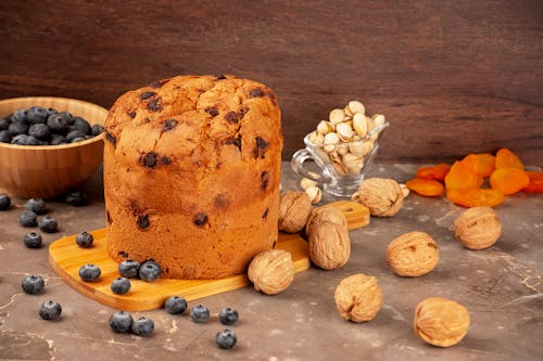 Free Walnuts and Blueberries Scattered Around a Cutting Board with Panettone Cake Stock Photo