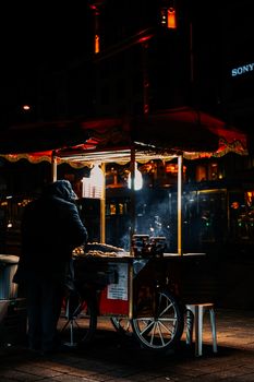 A street vendor cooks food at night under glowing lights, creating a vibrant urban atmosphere.
