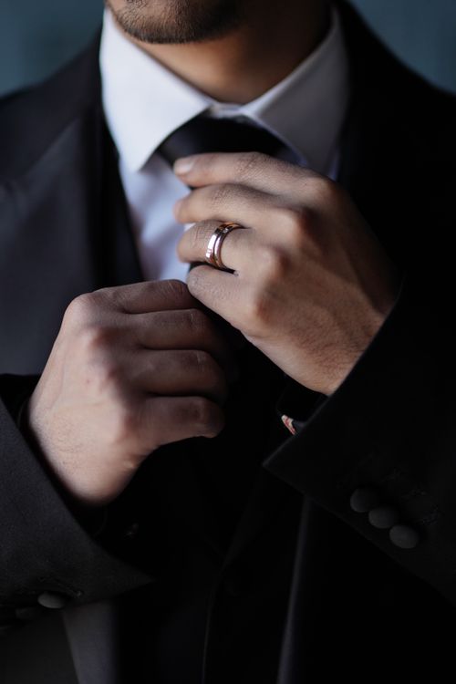 Free Sophisticated man adjusts necktie with ring, showcasing elegance and fashion. Stock Photo