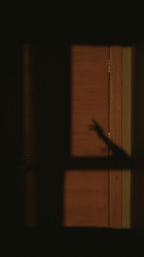 Free Abstract shadow of a hand reaching on a dimly lit wall for an artistic composition. Stock Photo