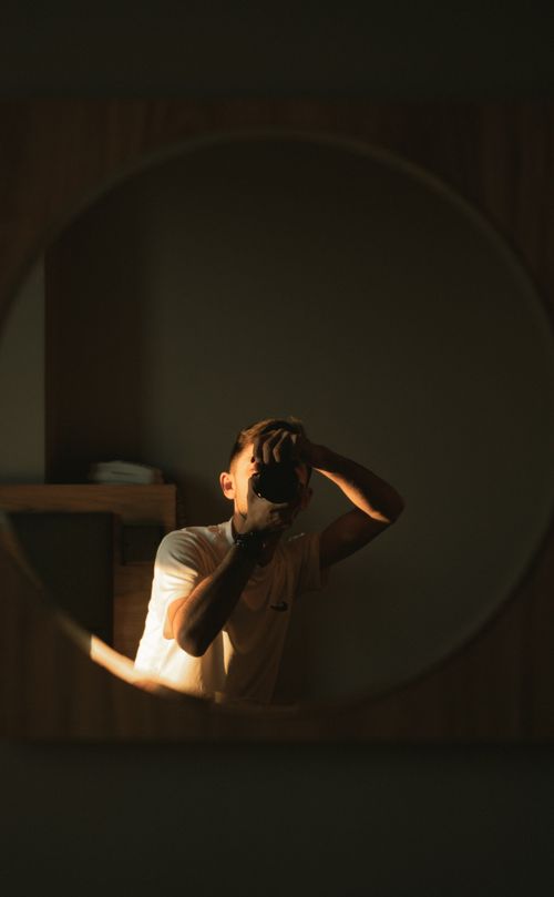 Free Capture of a photographer in a round mirror with a warm, moody ambiance. Stock Photo