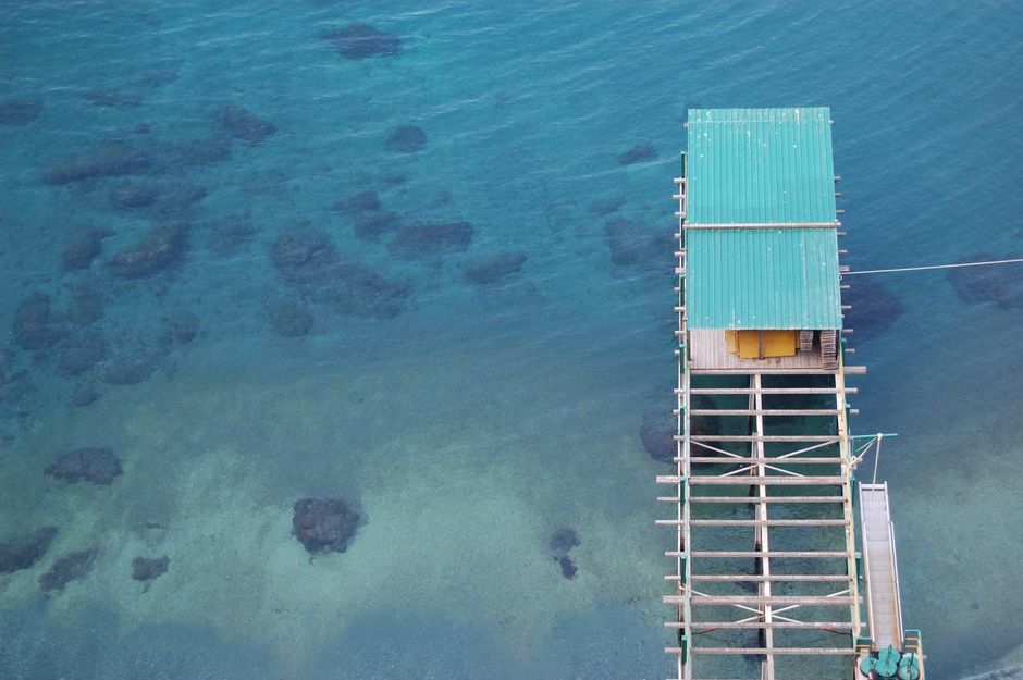 Aerial shot of a broken pier over clear blue waters, perfect for tranquility themes.