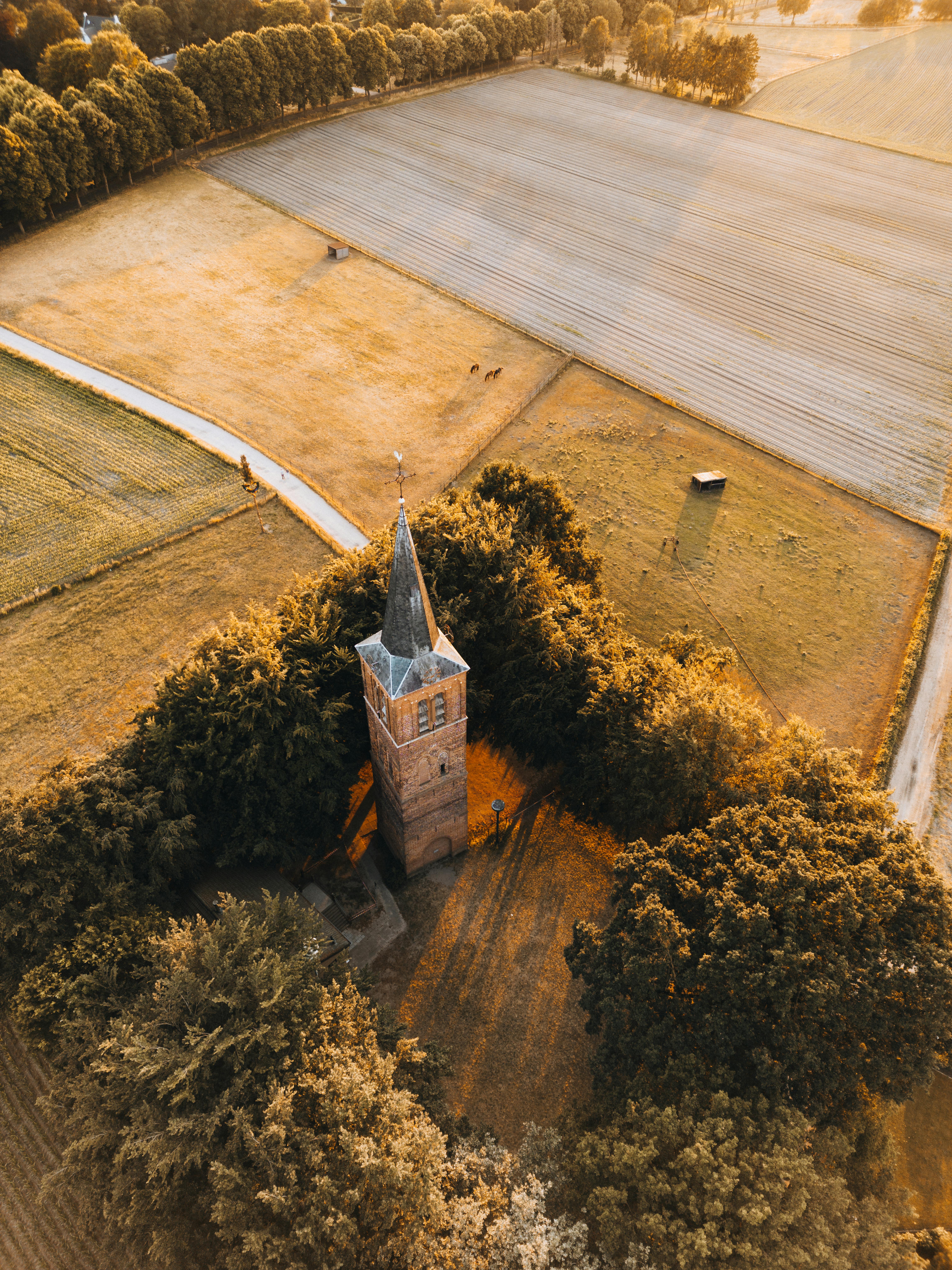 Drone shot capturing a solitary tower amidst a rural landscape at sunset.