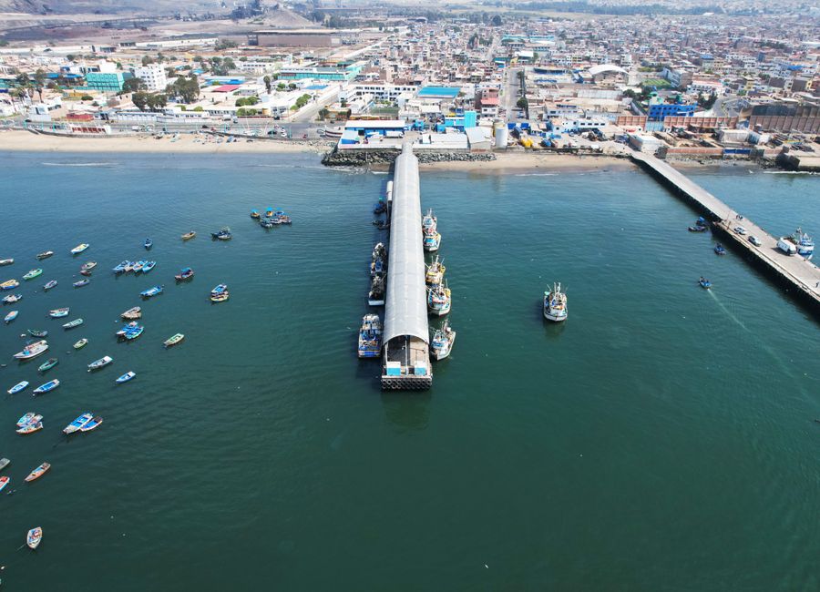 An aerial shot of Chimbote harbor, showcasing boats, urban landscape, and coastline.