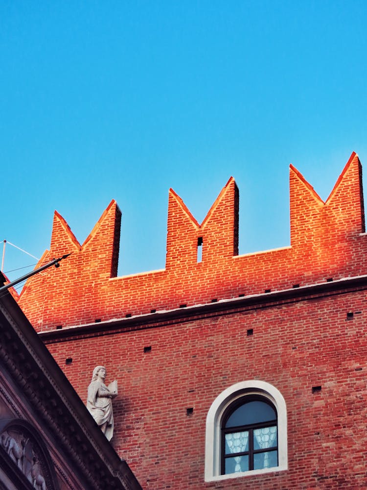 Sculpture On The Roof Next To The Wall Of A Brick Building