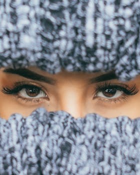 Elegant close-up of a woman's eyes framed by a knitted scarf, winter fashion.