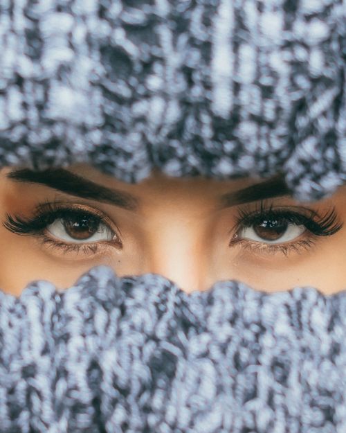 Free Elegant close-up of a woman's eyes framed by a knitted scarf, winter fashion. Stock Photo