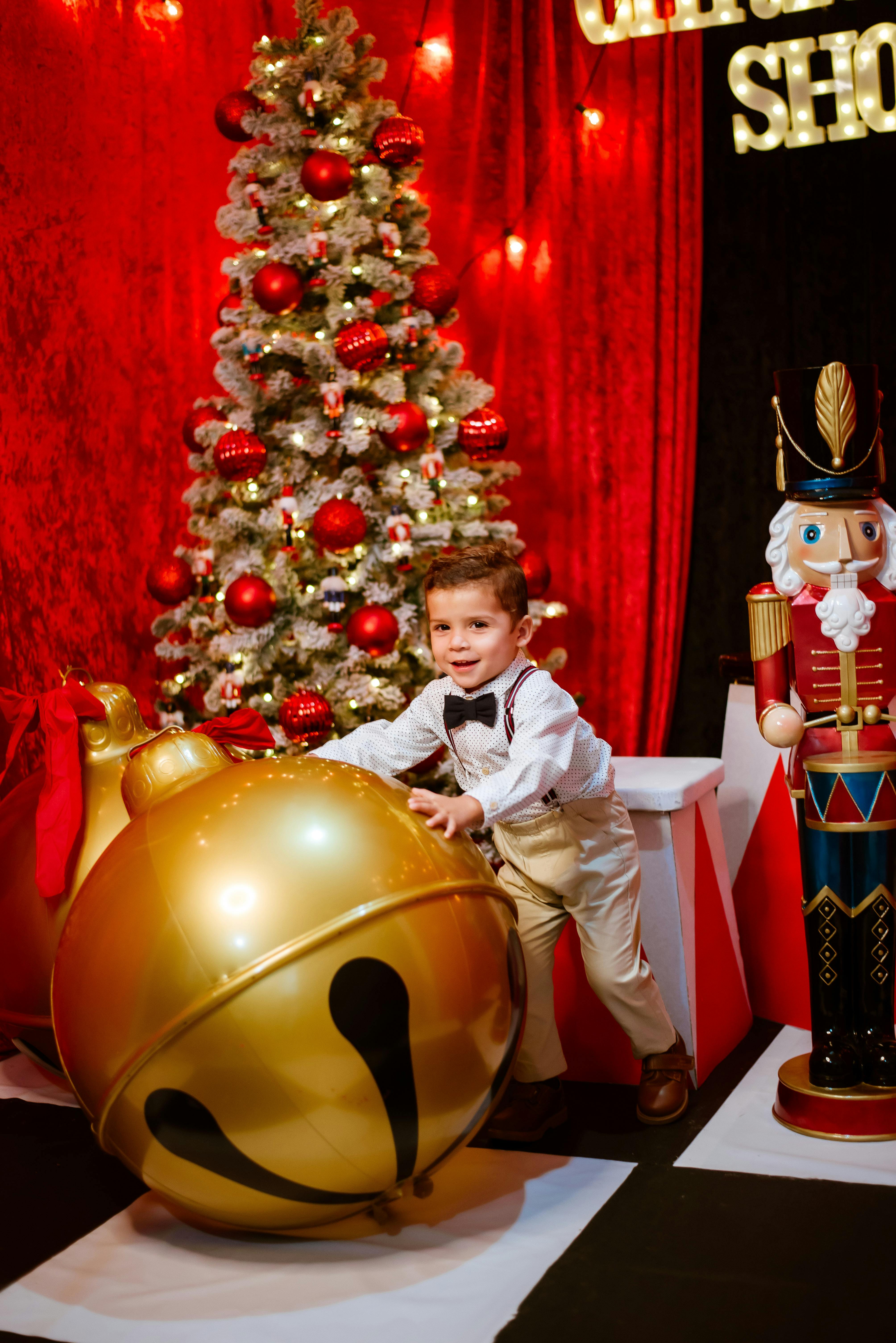 little boy playing with a large inflatable bell ball in christmas decoration