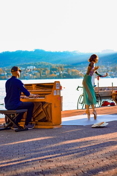 Free A pianist plays while a woman dances by the scenic Lake Zurich during sunset. Stock Photo