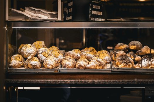 A tempting selection of fresh croissants displayed in a bakery window in Rome, Italy.