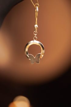 Closeup of a golden butterfly pendant, highlighting its intricate design and elegance.