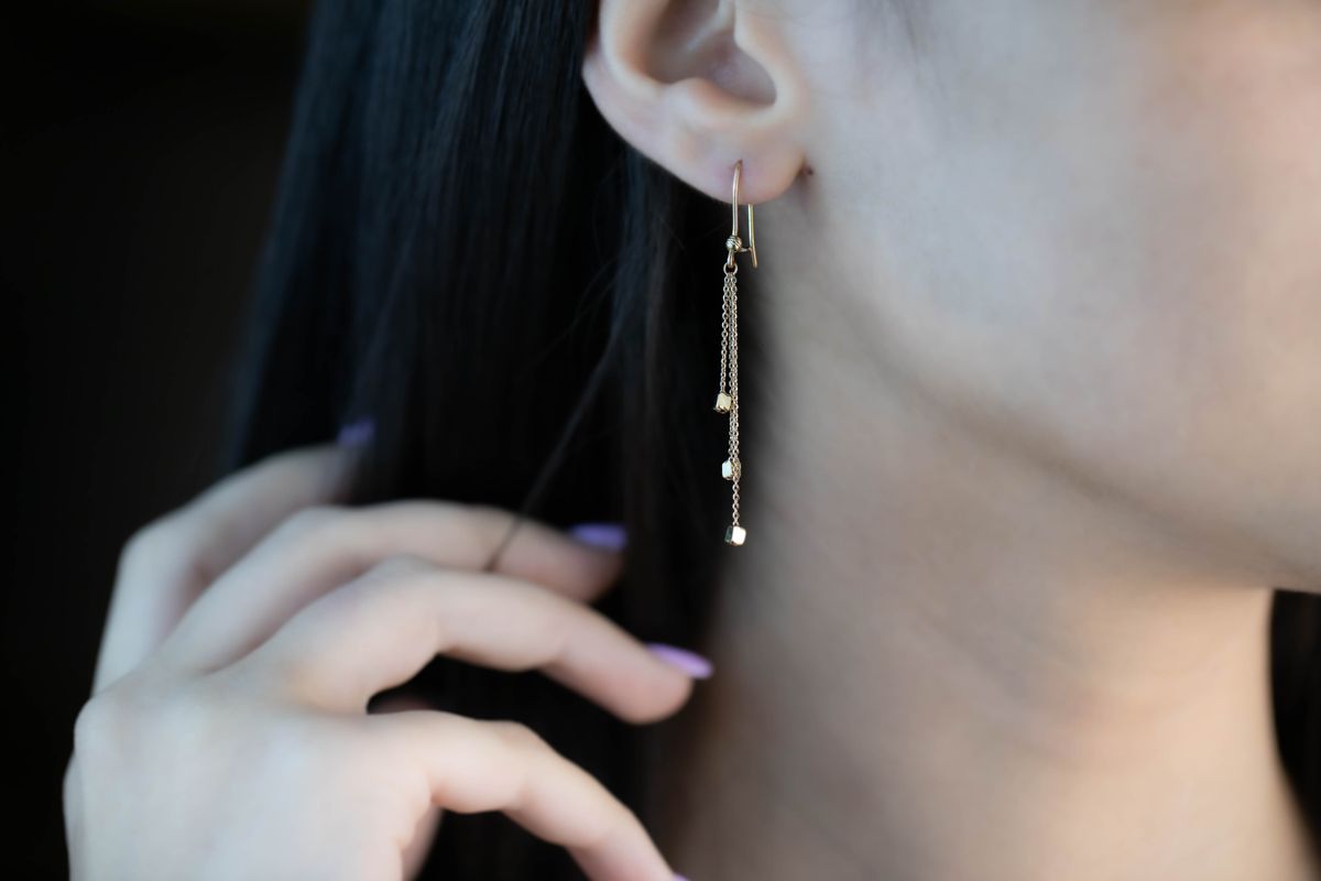 Gold drop earring shown in a close editorial crop