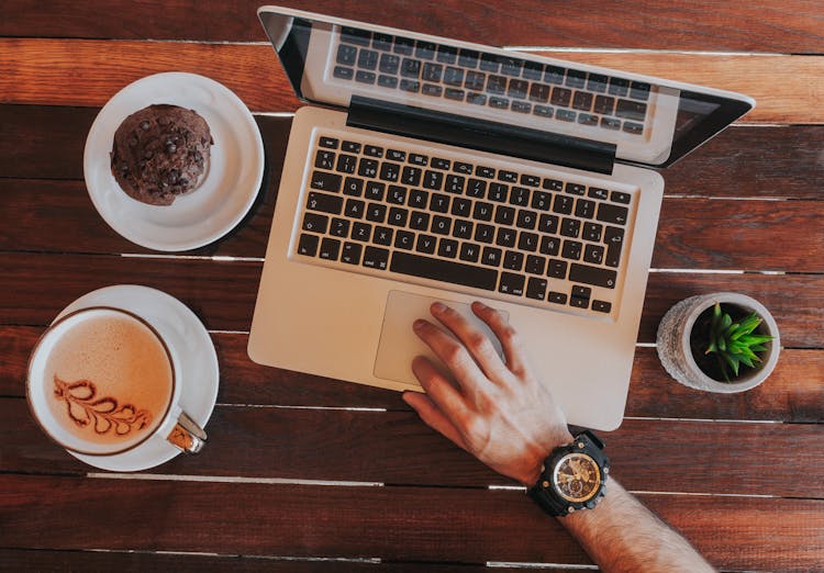 Man Hand On Laptop With Cookie, Coffee And Plant Around