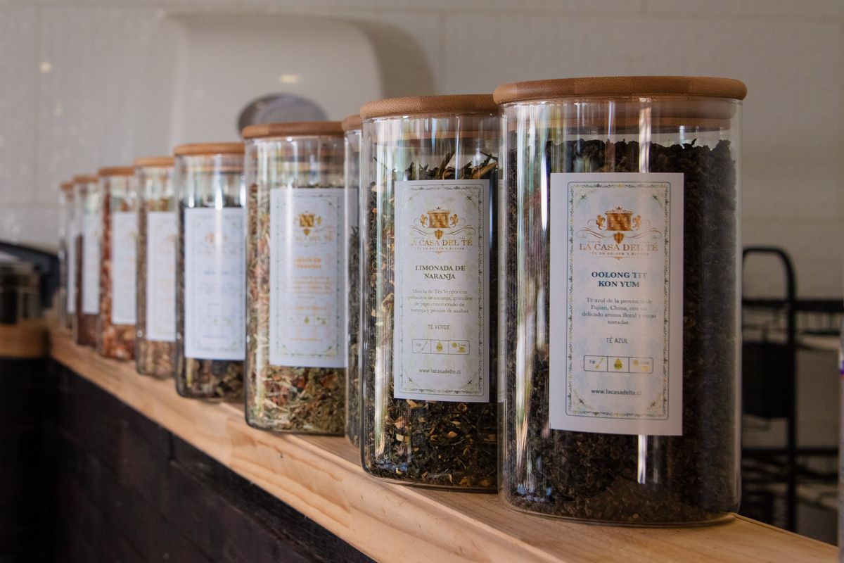 Glass jars of loose-leaf tea arranged on a wooden shelf