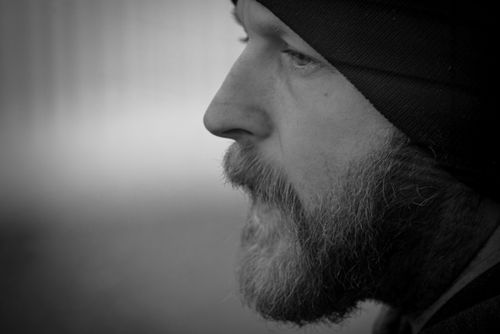 Free Close-up black and white portrait of a man with a beard and beanie, deep in thought. Stock Photo